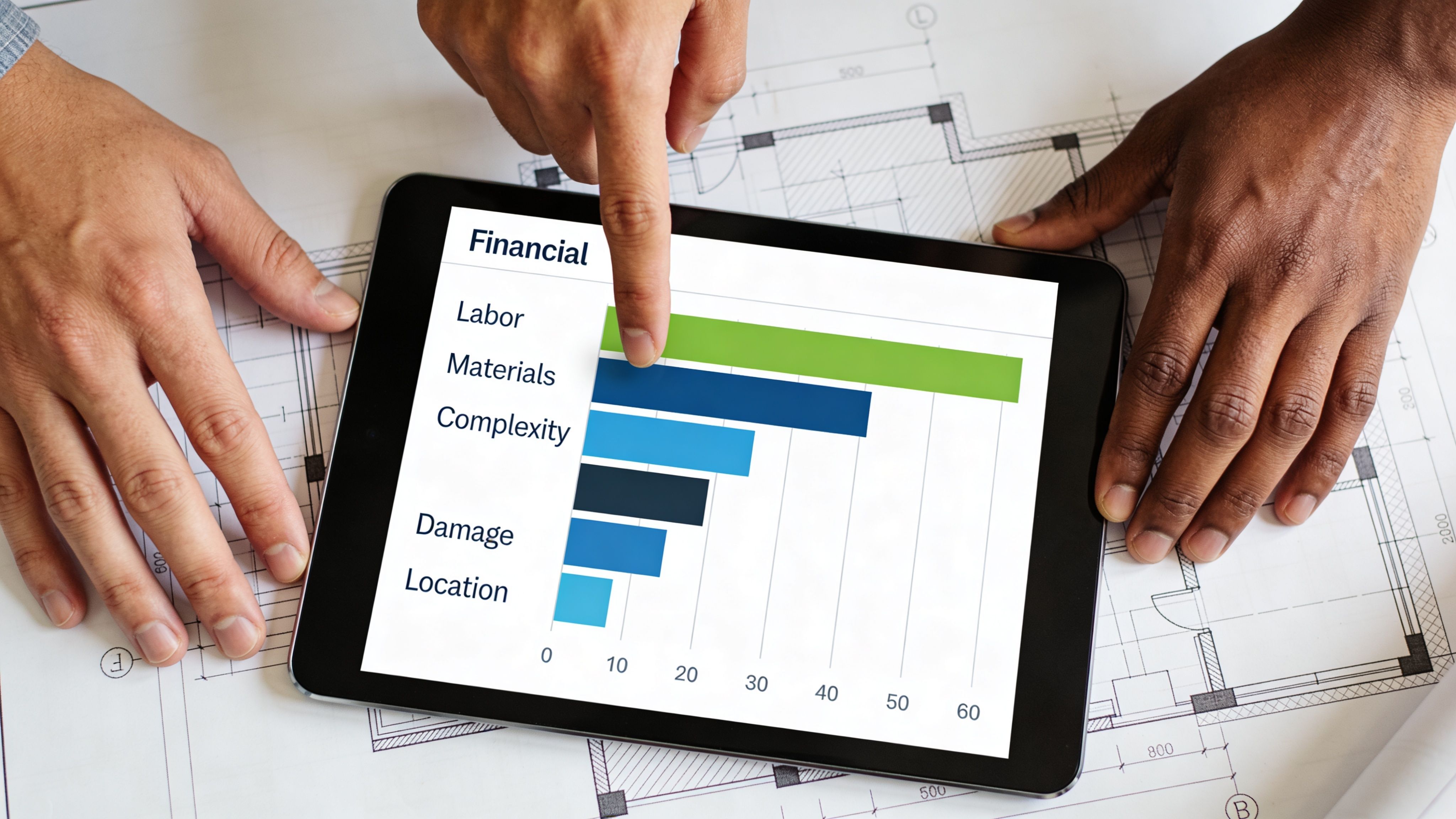 Two people reviewing construction costs and project estimates on a tablet screen with a digital bar chart.
