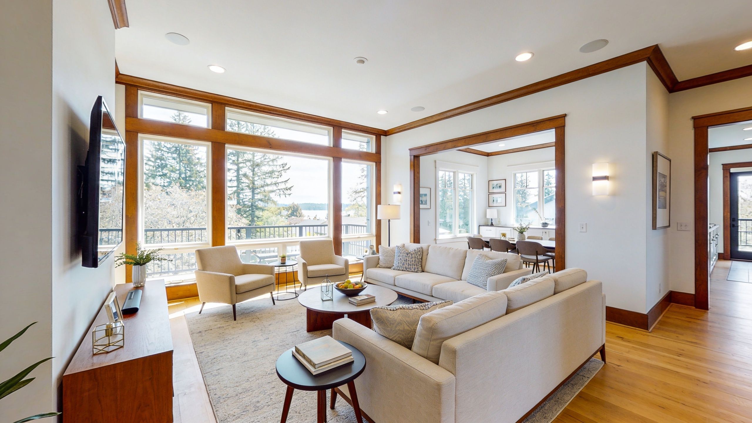 A modern and bright living room featuring a comfortable beige sofa, armchairs, and floor to ceiling windows.